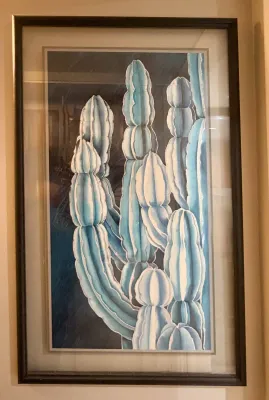 Framed watercolor painting depicting stylized blue-green cacti, presented in a double mat and a dark wood frame.