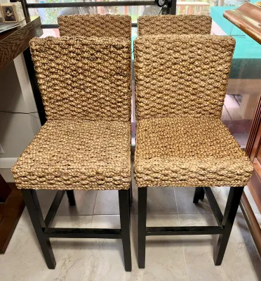 Set of four woven seagrass barstools with dark wood legs, showing a textured coastal style.