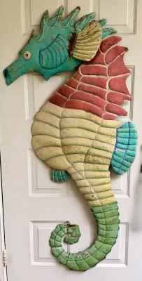 Large painted metal seahorse wall hanging, featuring a colorful multi-toned finish with some weathering and rust spots.