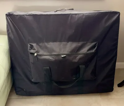 Master Massage portable massage table in a black zippered carrying case with a front storage pocket.