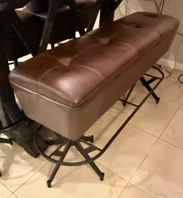 Contemporary tufted brown leather bench with a black metal base and integrated footrest.