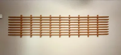 Mid-century modern style wooden wall-mounted rack or trellis, featuring a minimalist grid design with horizontal slats.