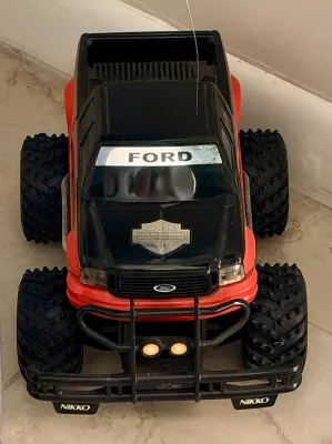 Vintage Nikko Ford Harley-Davidson edition RC monster truck, featuring a black and orange body with large knobby tires.