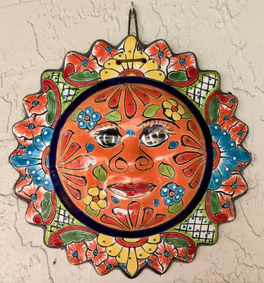 Mexican Talavera ceramic sun face wall plaque, featuring vibrant hand-painted floral motifs in orange, blue, yellow, and green.