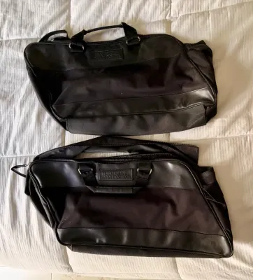 Pair of black Harley-Davidson saddlebag liner bags, featuring zippered closures, carrying handles, and embossed leather logo patches.