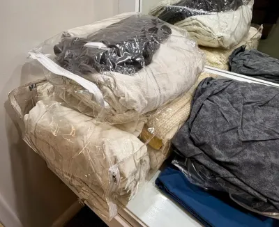 Assorted bedding and linens, including sheets and blankets, stored in clear zippered plastic organizer bags.