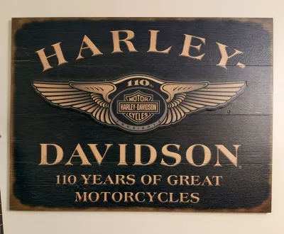 Harley-Davidson 110th Anniversary wooden sign, featuring carved lettering and the winged bar and shield logo, commemorating 110 years of...