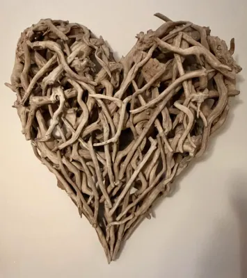 Heart-shaped wall art crafted from interwoven pieces of natural driftwood, presenting a rustic, coastal aesthetic.