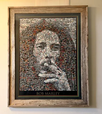 Framed Bob Marley photomosaic poster, featuring a portrait composed of smaller images, housed in a rustic weathered wood frame.