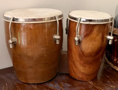 Vintage wooden bongo drums with natural heads and chrome hardware, showing some wear from use.