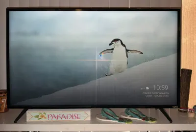 Vizio flat-screen television on a stand, shown powered on and displaying a penguin image.