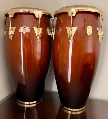 Pair of LP Caliente conga drums featuring a polished wood finish with gold-tone hardware.