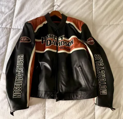 Harley-Davidson leather motorcycle jacket in black, orange, and white, featuring embroidered branding on the chest and sleeves.