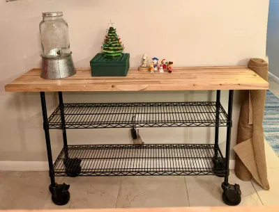 Industrial-style rolling kitchen cart featuring a butcher block wood top, black wire shelving, and heavy-duty casters.