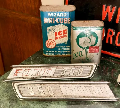 Vintage Wizard Dri-Cube and ICIT reusable ice cans alongside a pair of weathered Ford 350 metal truck emblems.