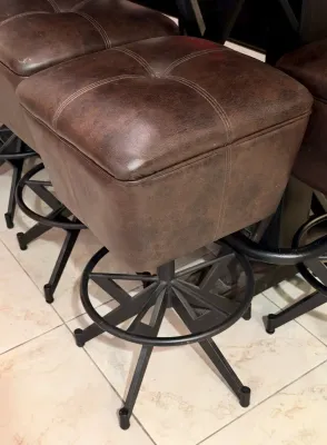 Contemporary swivel bar stools featuring tufted dark brown faux leather seats and black metal bases with integrated circular footrests.