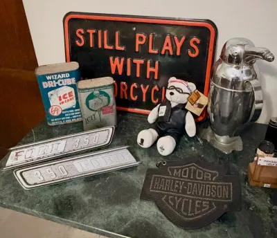 Assorted vintage collectibles, including a 'Still Plays With Motorcycles' metal sign, a chrome penguin cocktail shaker, vintage...