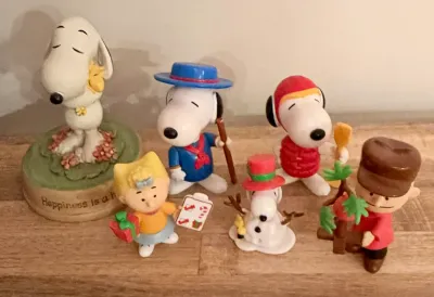 Collection of vintage Peanuts figurines, including a Snoopy and Woodstock music box, Sally Brown, Linus, and various Snoopy characters in...