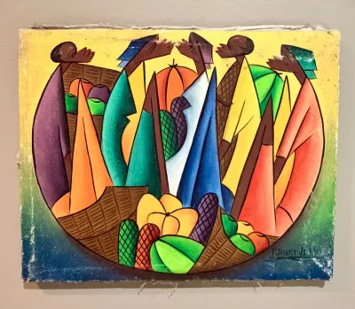 Haitian market scene painting on canvas, featuring stylized figures and colorful produce, signed by the artist in the lower right corner.
