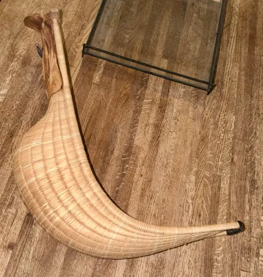Vintage woven wicker jai alai cesta, showing a curved basket design with a leather hand glove attachment.