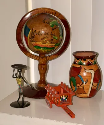 Collection of hand-painted souvenir items, including a wooden globe depicting Haiti, a miniature Costa Rican oxcart, a ceramic vase, and...