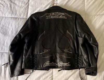 Harley-Davidson black leather motorcycle jacket featuring embroidered branding, a large spade graphic on the back, and lace-up side details.