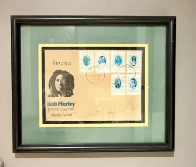 Framed Bob Marley Jamaica Official First Day Cover dated October 20, 1981, featuring commemorative stamps and postmarks, presented in a...