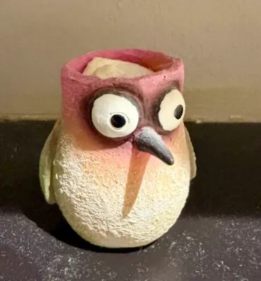 Whimsical ceramic bird figurine with a hollow top, featuring large googly-style eyes, a long beak, and a textured pink and white finish.