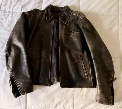 Star Motorcycles distressed brown leather riding jacket with zippered pockets and cuffs, showing natural wear and patina.