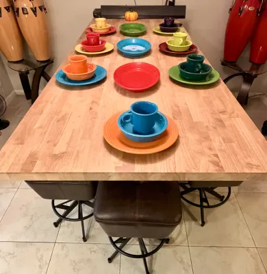 Large butcher block dining table paired with swivel barstools, displaying a colorful collection of Fiesta ceramic dinnerware.
