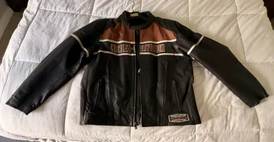Harley-Davidson leather motorcycle jacket in black, brown, and cream, featuring embroidered chest branding and zippered pockets.