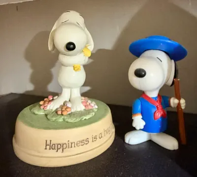 Vintage Snoopy collectibles, featuring a ceramic music box reading "Happiness is a hug" and a plastic Beagle Scout Snoopy...