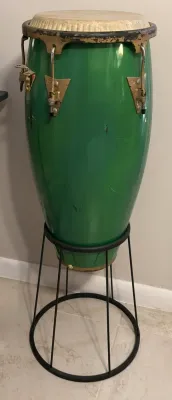Vintage green LP (Latin Percussion) conga drum on a black metal stand, showing some wear and scuffs on the shell and hardware.