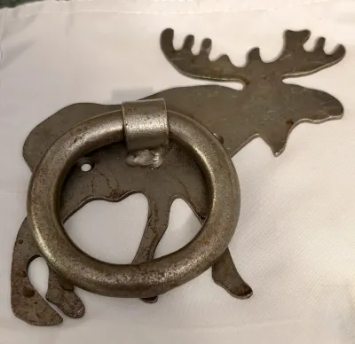 Rustic cast iron moose door knocker with a weathered, distressed finish.