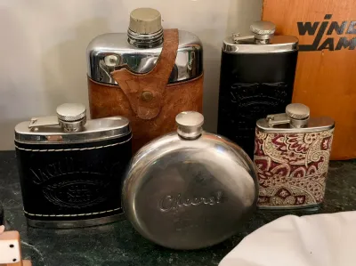 Collection of vintage hip flasks, including a round stainless steel flask engraved with "Cheers!", two Jack Daniel's...