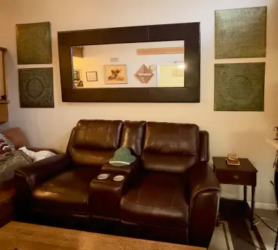 Brown leather double reclining loveseat with a center console and cup holders, paired with a large dark-framed wall mirror and decorative...