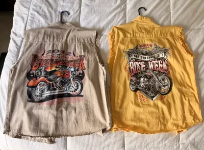 Two sleeveless denim shirts with Daytona Beach Bike Week 2012 graphics on the back, one in tan and one in yellow, both featuring raw-edge...
