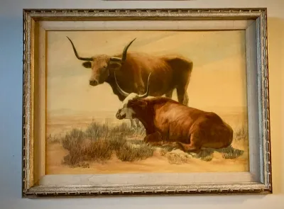 Framed oil painting depicting two Texas Longhorn cattle in a desert landscape, signed and dated 1959, housed in a rustic carved wooden...
