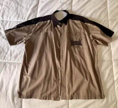 Harley-Davidson short-sleeve button-up shirt in tan and black, featuring embroidered chest graphics and dual chest pockets.