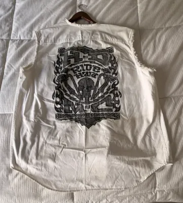 White sleeveless denim shirt featuring a large black Harley-Davidson 'Ride Hard' skull graphic on the back, with frayed...
