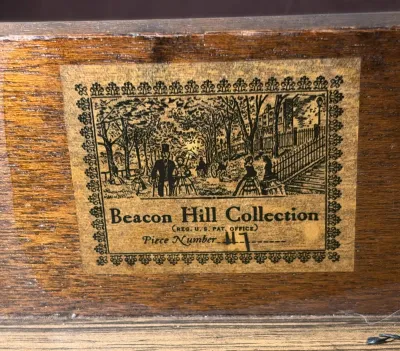 Vintage Beacon Hill Collection maker's label affixed to a wooden furniture piece, featuring an illustrated Victorian park scene and...