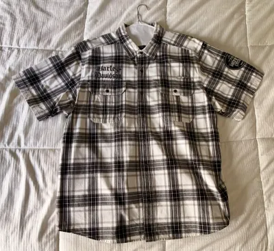 Harley-Davidson short-sleeve button-down plaid shirt in black, white, and grey, featuring embroidered branding on the chest and a patch...