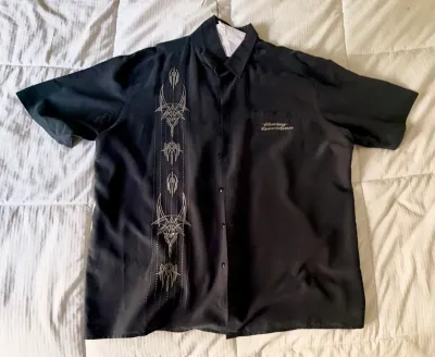 Harley-Davidson short-sleeve button-up shirt in black, featuring embroidered pinstripe graphics on the right side and a small logo on the...