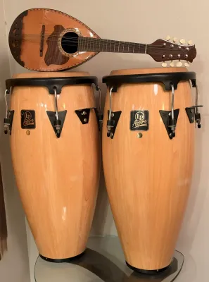 Pair of LP Aspire wood conga drums in a natural finish, shown with a vintage teardrop mandolin resting on top.