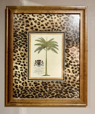 Framed botanical print of a palm tree with a royal crest, matted in a leopard print fabric and set in a gold-finished wooden frame.