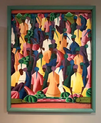 Haitian market scene oil painting on canvas, signed by the artist and housed in a simple teal-painted wooden frame.