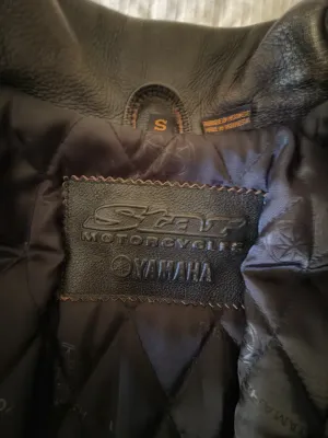 Interior label of a Star Motorcycles Yamaha black leather riding jacket, size small, featuring a quilted lining.