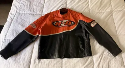 Harley-Davidson leather motorcycle jacket in orange and black, featuring quilted shoulder details and embroidered brand patches.