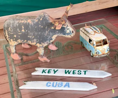 Rustic metal bull sculpture and a vintage-style Volkswagen bus model with surfboards, displayed alongside hand-painted wooden directional...