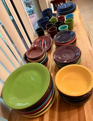 Large collection of colorful Fiesta dinnerware, including plates, bowls, and mugs in various signature glazes.